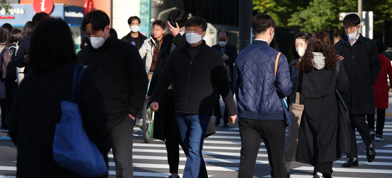 Pedestrians in jackets walk outdoors in central Seoul on Tuesday. (Yonhap)