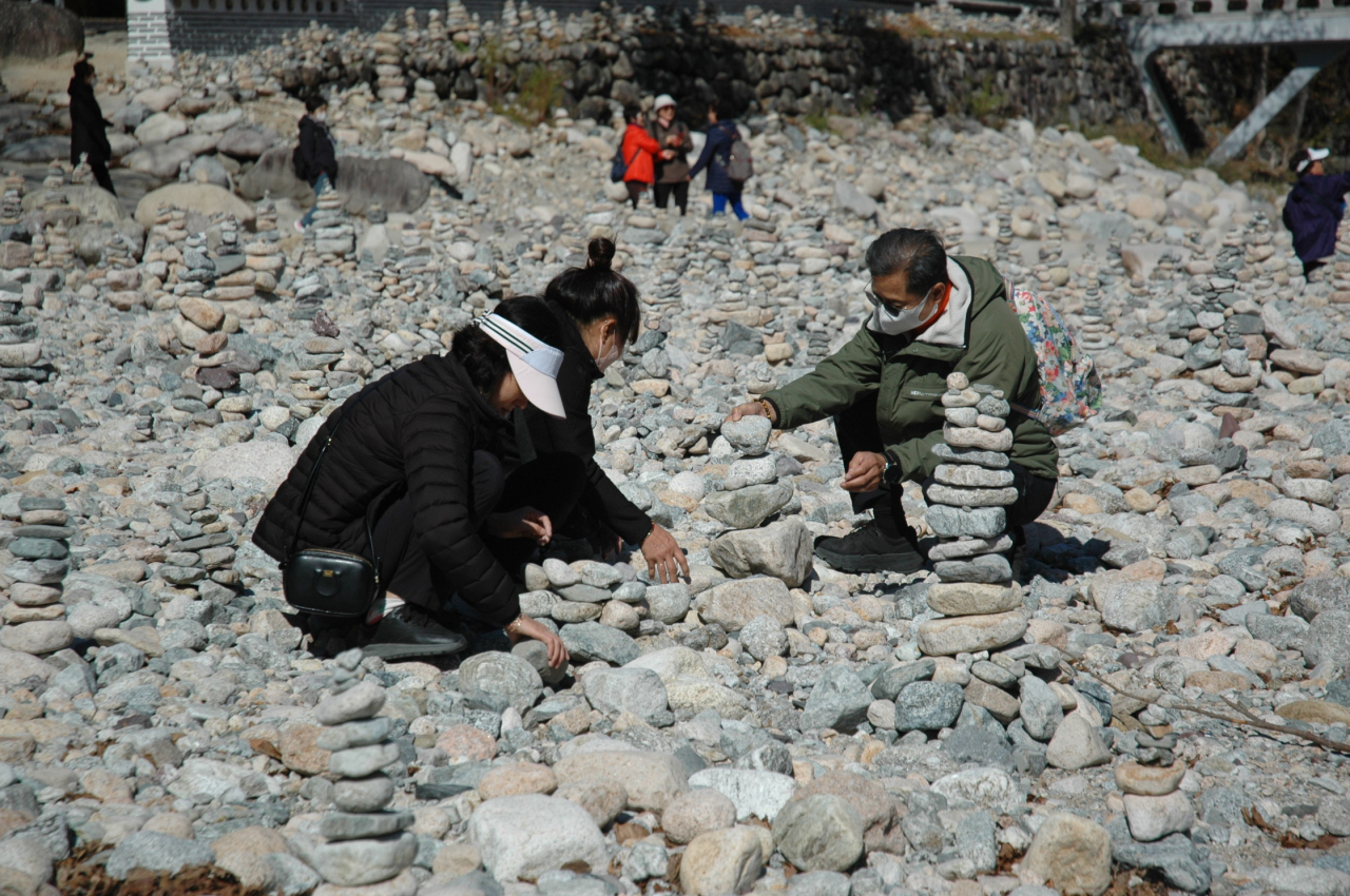A family stacks stones outside Baekdamsa in Inje, Gangwon Province, Tuesday. (Lee Si-jin/The Korea Herald)