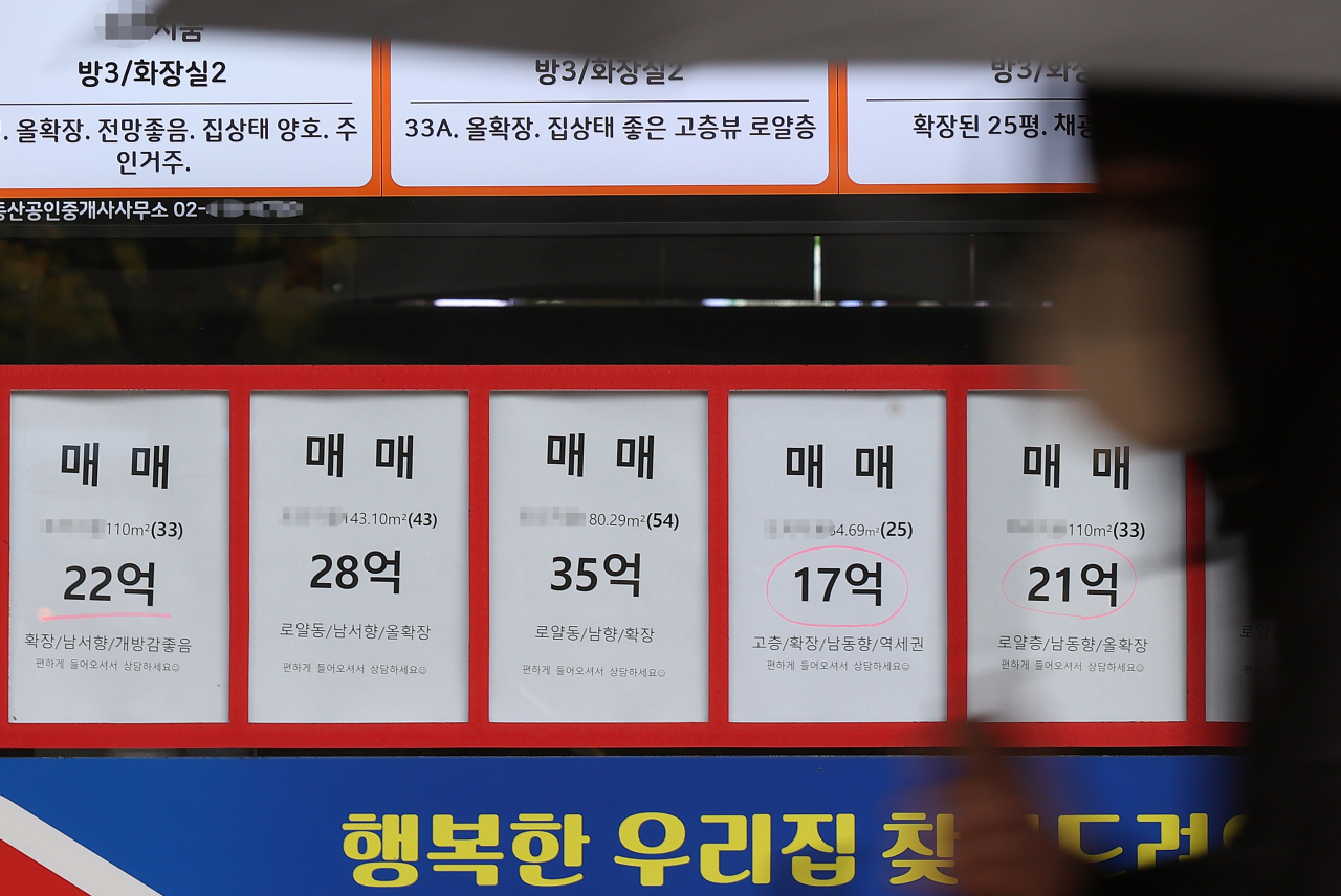 Postings of asking prices of home sellers are attached on the window of a real estate agency in Seoul earlier this month. (Yonhap)