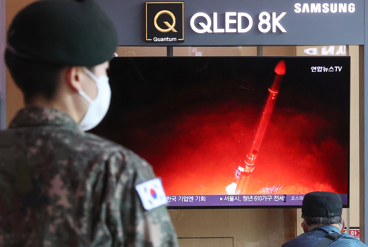Passersby watch a TV report of North Korea`s missile launch at Seoul Station. (File Photo - Yonhap)