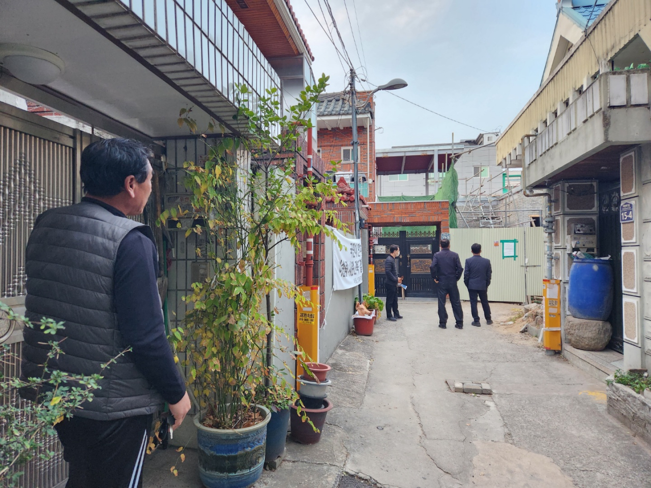 A man surnamed Jang looks out at the construction site in front of his home as three officials from Daegu's Buk-gu Office inspect the area, Wednesday. (Choi Jae-hee/The Korea Herald)