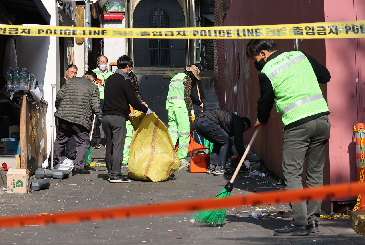 Sanitation workers clean the scene of the Itaewon crowd surge on Friday. (Yonhap)