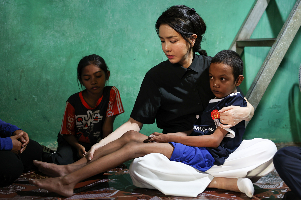 First lady Kim Keon-hee holds a child on her lap in her visit to his home in Phnom pen, Cambodia on Saturday. (Yonhap)