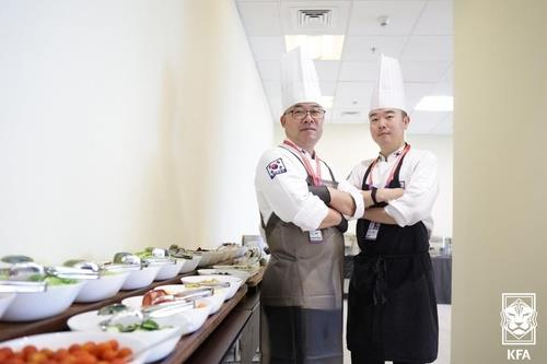 Kim Hyung-chae (left) and Shin Dong-il, chefs for the South Korean men's national football team at the FIFA World Cup in Qatar, pose for photos at the team dining hall at Le Meridien City Center, Doha, the team's official hotel during the tournament on Thursday. (Korea Football Association)