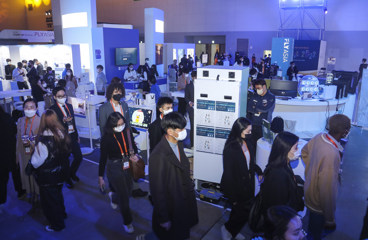 Attendees look around exhibition booths at the Fly Asia startup expo held at Bexco in Busan on Tuesday. (Yonhap)