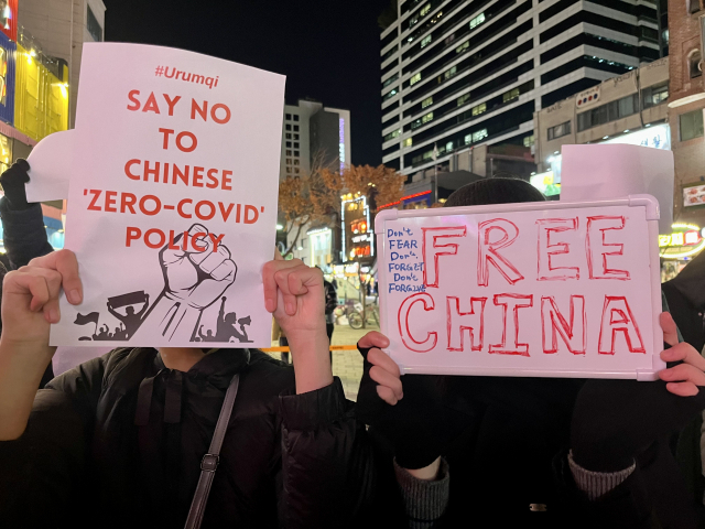 Chinese protesters in their 20s hold signs in support of the China's city Urumqi and that say, “Don’t fear, don’t forget, don’t forgive.” They declined to be interviewed because they feared they could be identified by the Chinese authorities. (Kim Arin/The Korea Herald)