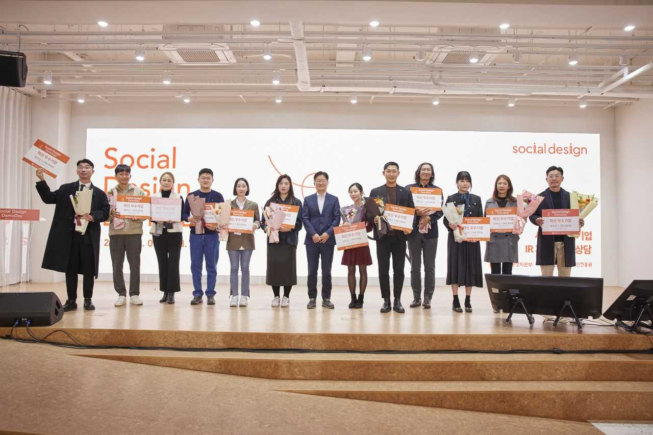 Korea Institute of Design Promotion Executive Managing Director Yoo Kwan-hyung (center) poses Wednesday with participants of the Social Design Demo Day event in central Seoul. (KIDP)