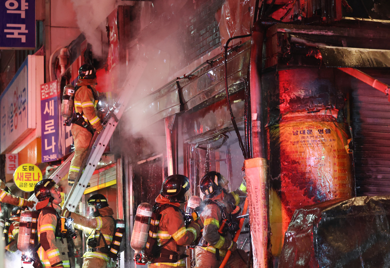 Firefighters work to contain a fire at a building in Namdaemun market, central Seoul, on Wednesday evening. (Yonhap)