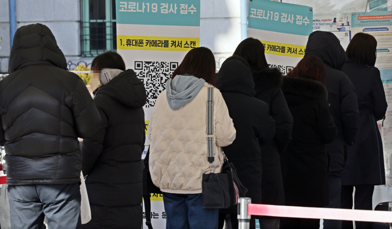 People wait in line to take COVID-19 tests at a temporary testing booth at Seoul Station on Monday. (Yonhap)
