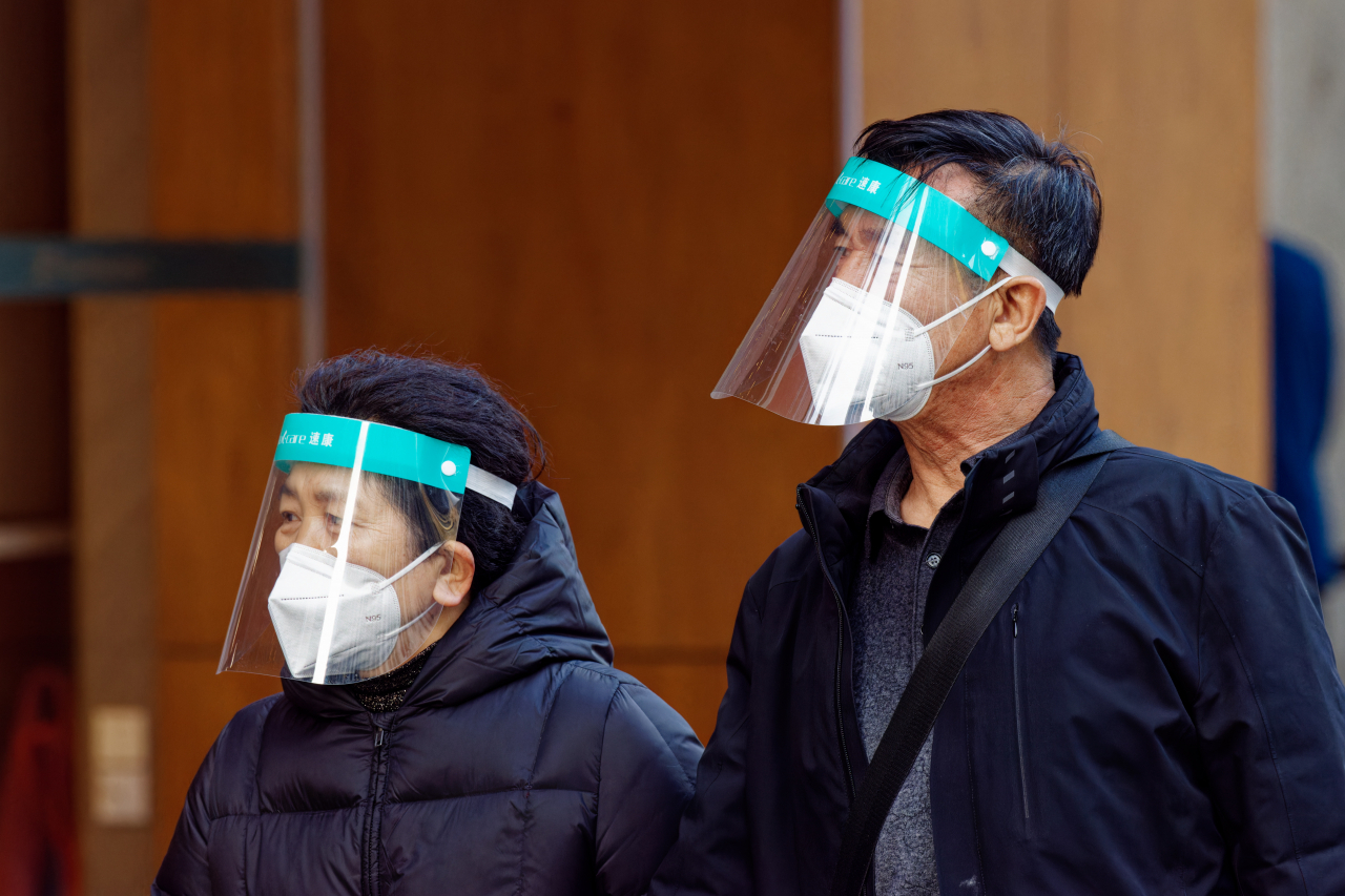 A couple wearing face shields for protection walk on the street, in Shanghai, China, 14 December 2022. (EPA-Yonhap)