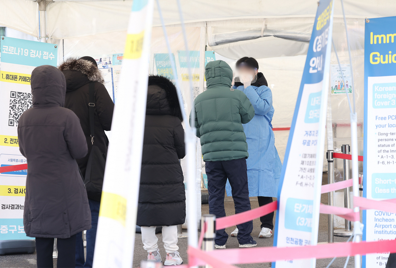 People wait in line to get tested for the coronavirus at a testing center near Seoul Station on Sunday. (Yonhap)