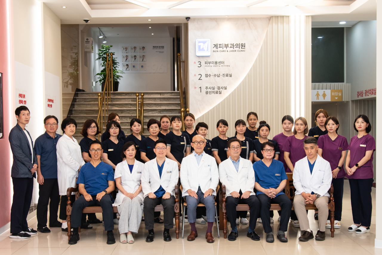 KYE Dermatology Clinic director Kim Shin-han (third from left, front row), and honorary director Kim Joong-ho (fourth from left, front row) pose for a pictrue with the clinic's employees. (KYE Dermatology Clinic)
