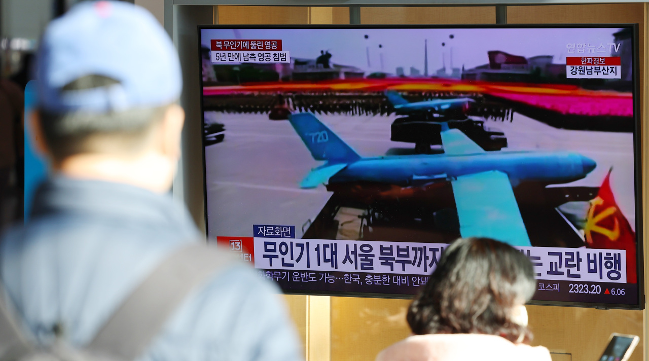 Passersby watch a news report on North Korean drones` infiltration into South Korean airspace at Yongsan Station in Seoul on Tuesday. (Yonhap)