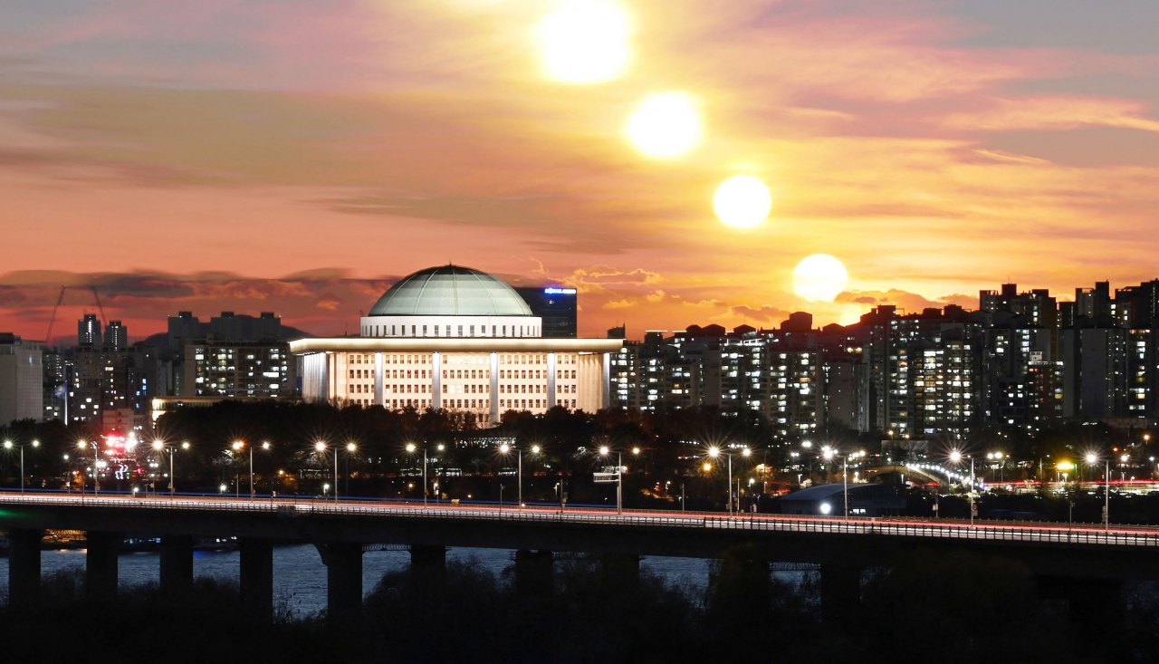 The sun sets behind the National Assembly in Yeouido, Seoul, as a year marked by sharp political confrontations draws to a close. (The Korea Herald)