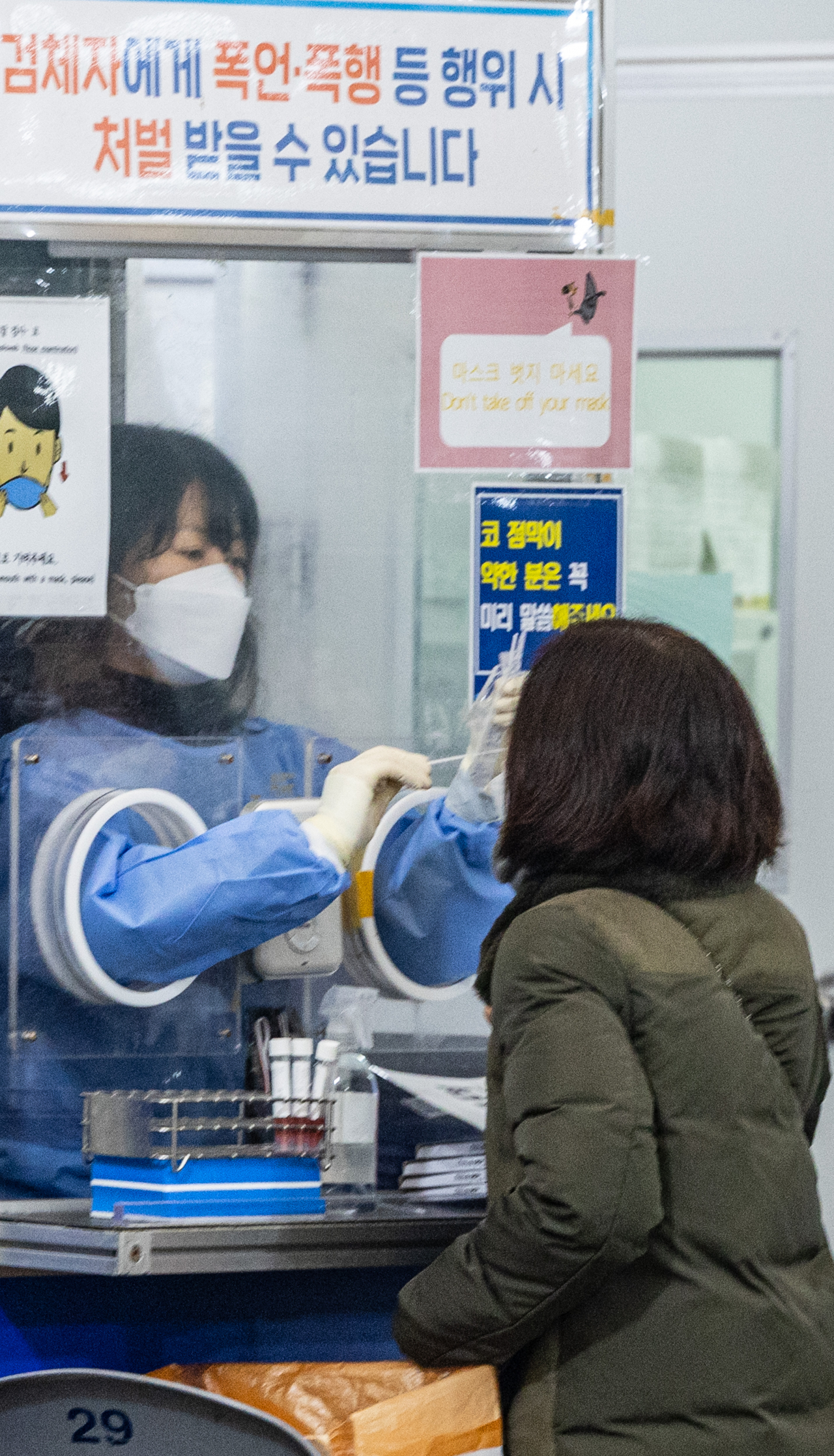 A medical worker conducts a coronavirus test on a woman at a public health facility in Seoul's Songpa Ward on Friday. South Korea's daily new COVID-19 cases came to 65,207, falling for the third consecutive day amid the government's efforts to contain the virus' wintertime resurgence. (Yonhap)