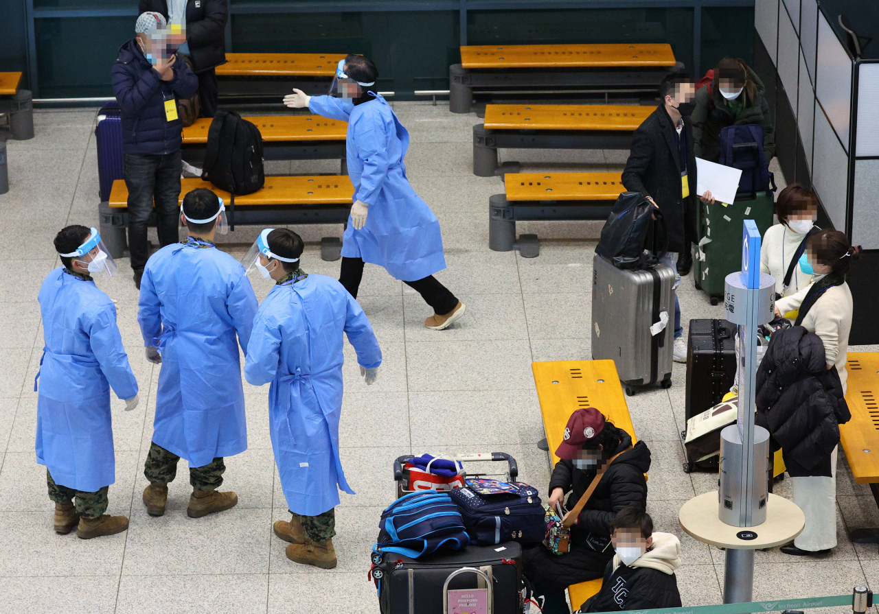 Quarantine officials guide travelers at Incheon International Airport's Terminal 1, west of Seoul, Tuesday. (Yonhap)