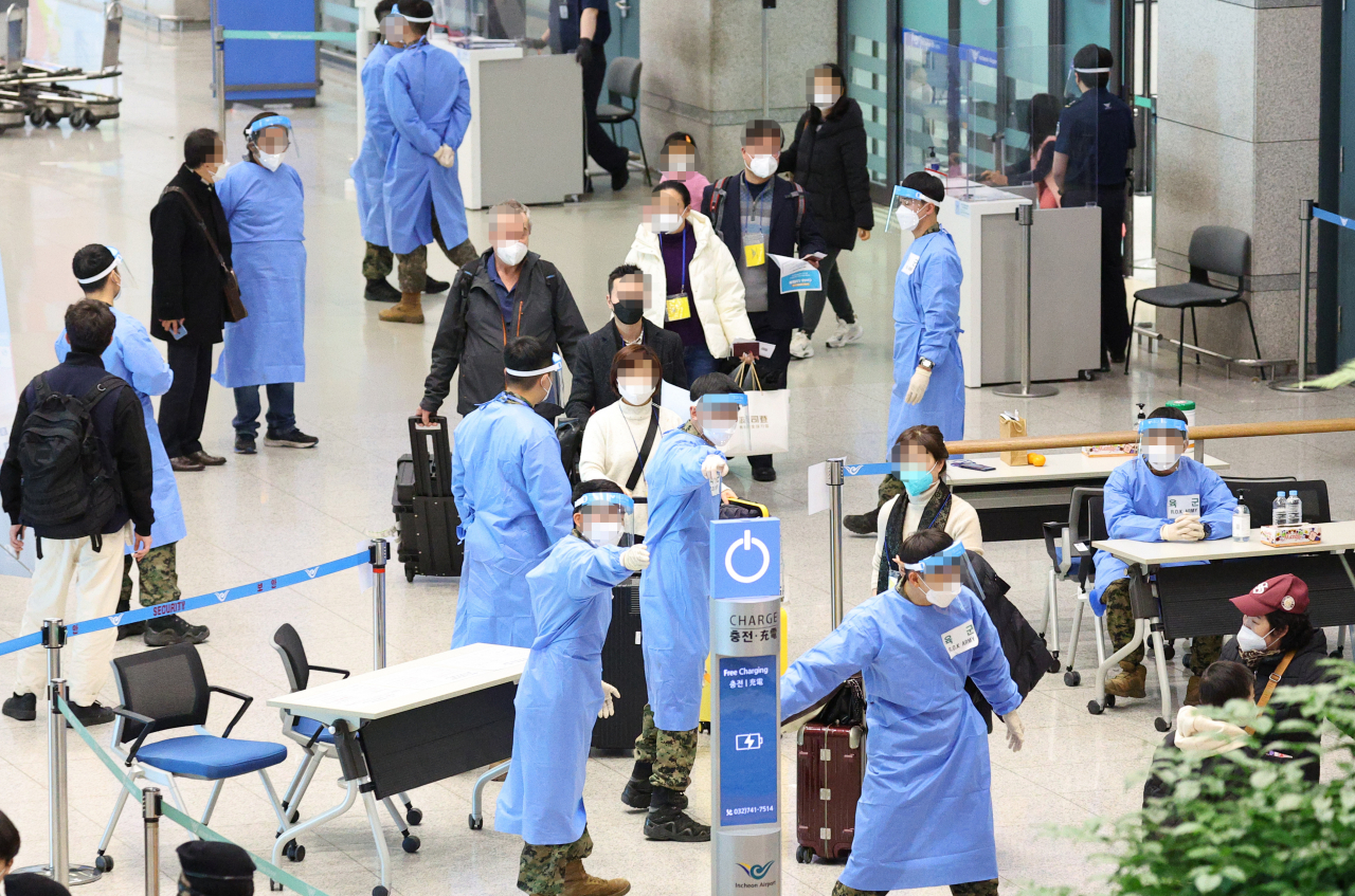 Entrants follow the quarantine officials after entering the country through Incheon International Airport Terminal 1, Yeongjong Island, Incheon, Tuesday. (Yonhap)