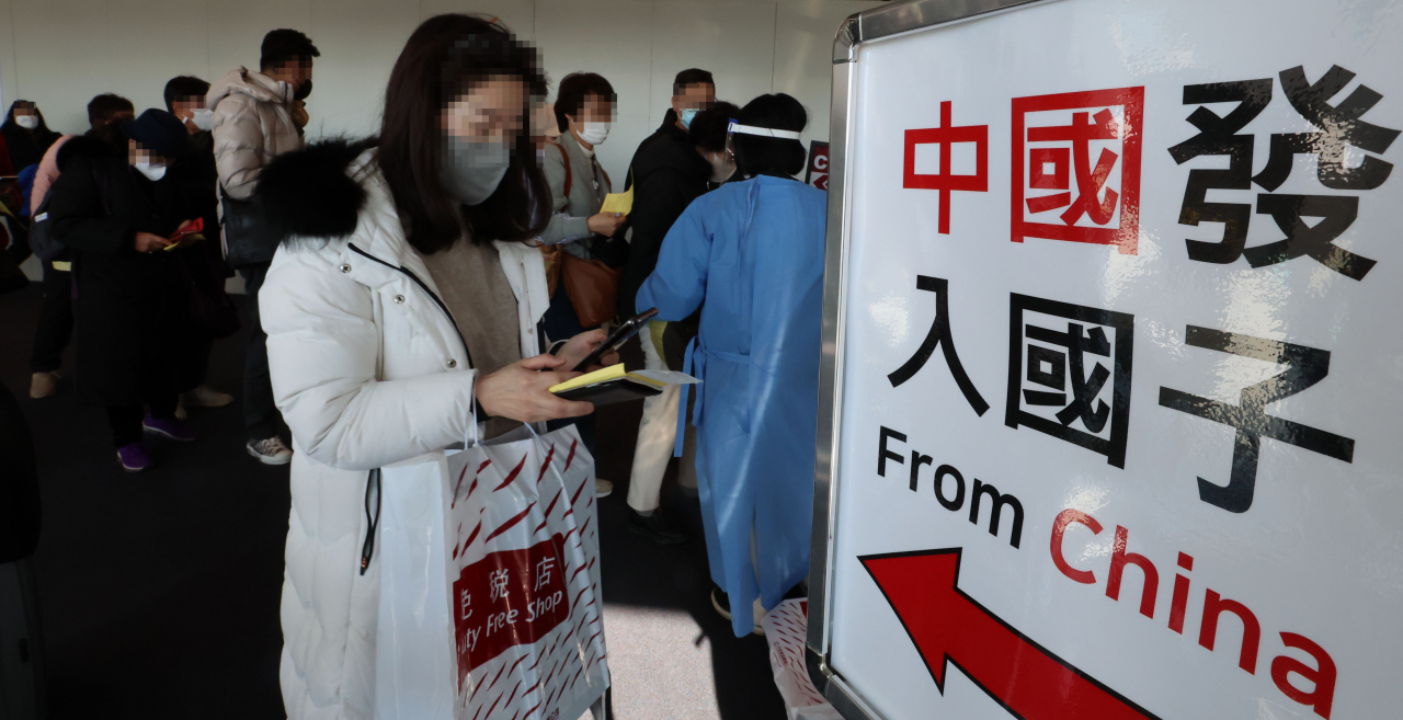 A quarantine official in a blue gown guides travelers arriving from China to undergo a PCR test at Incheon Airport, Monday. (Yonhap)