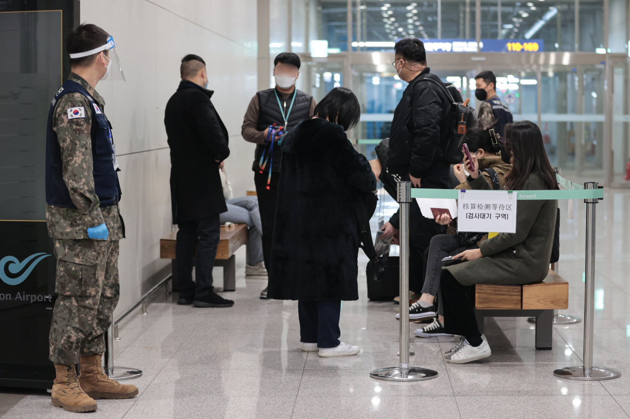 Inbound passengers from China, Hong Kong and Macao wait to take COVID-19 tests at Incheon International Airport, west of Seoul, on Monday. (Yonhap)