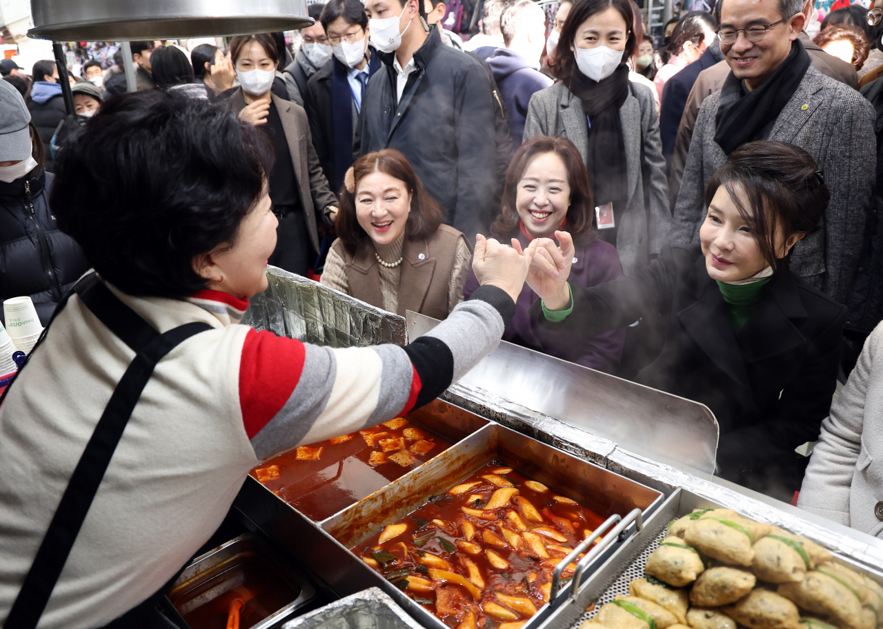 First lady Kim Keon Hee makes a pinky promise with a merchant to visit the shop again after tasting dumplings and other food at Seomun Market in Daegu on Wednesday. (Yonhap)