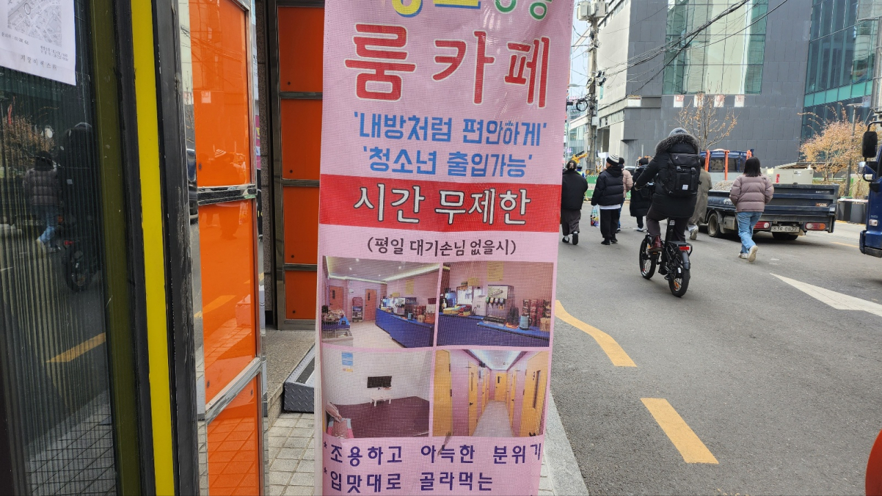 Pedestrians walk by a banner advertising a room cafe in Mapo-gu, Seoul, which mentions 