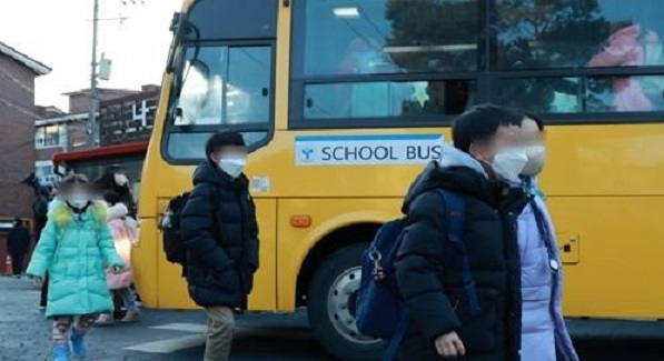 Students wearing face masks get off a school bus in Seoul on Jan. 30, 2023. (Yonhap)