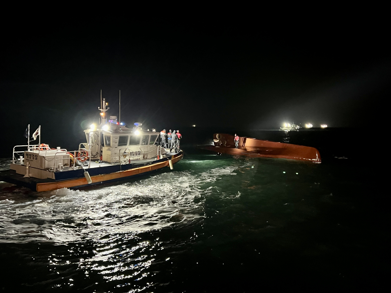 A rescue vessel attends to a 24-ton fishing boat that overturned off the coast of Sinan, South Jeolla Province. (Mokpo Coast Guard)