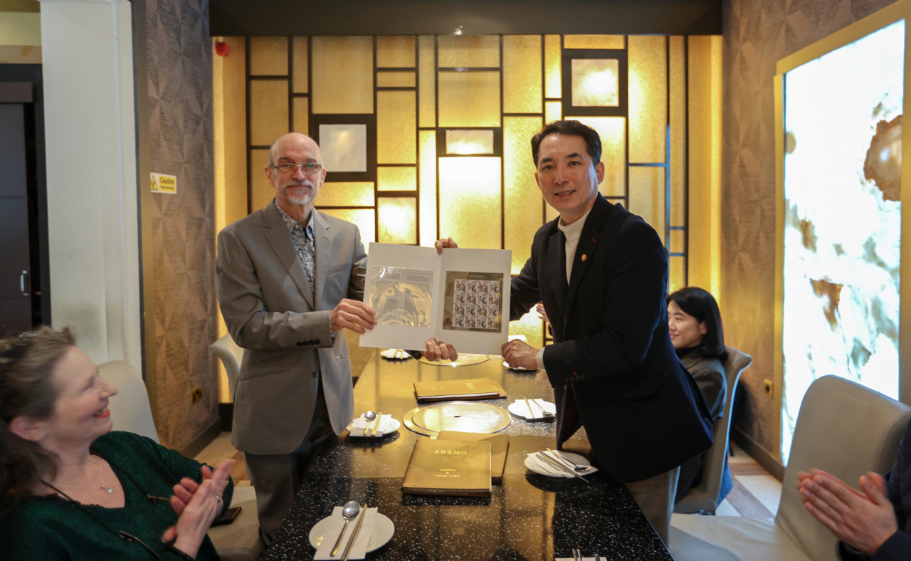 This photo shows Veterans Minister Park Min-shik (on the right) handing postal stamps commemorating Ernest Bethell, who reported on Japan's misdeeds against Korea during its 1910-45 colonial rule, to his grandson as they meet at a restaurant in London on last Friday (South Korean Veterans Ministry)