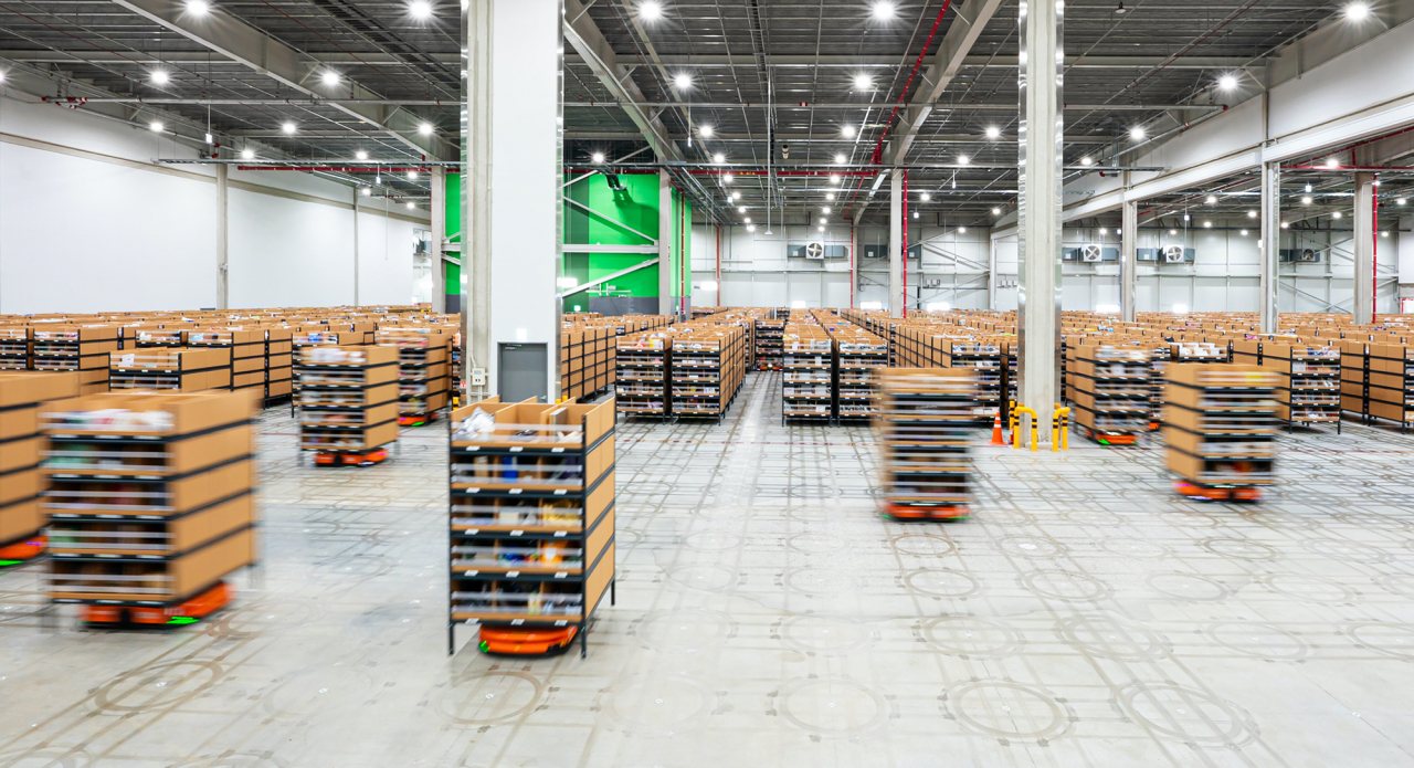 Automated Guided Vehicles carry items to a worker by following QR codes drawn on the floor. (Coupang)