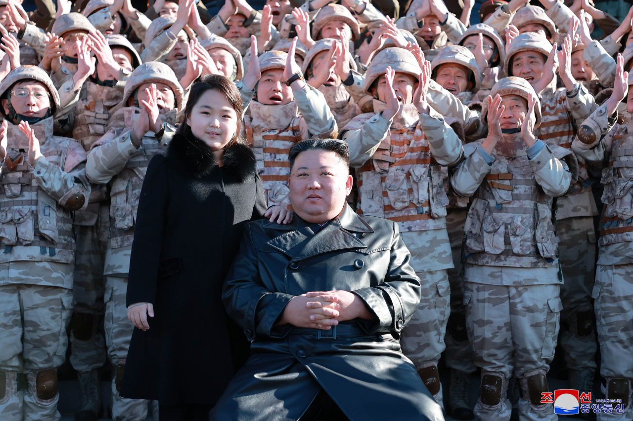 This photo, released by the Korean Central News Agency on Nov. 27, 2022, shows North Korean leader Kim Jong-un (right) with his daughter during a photo session with officials involved in this month's intercontinental ballistic missile launch. (Korean Central News Agency)