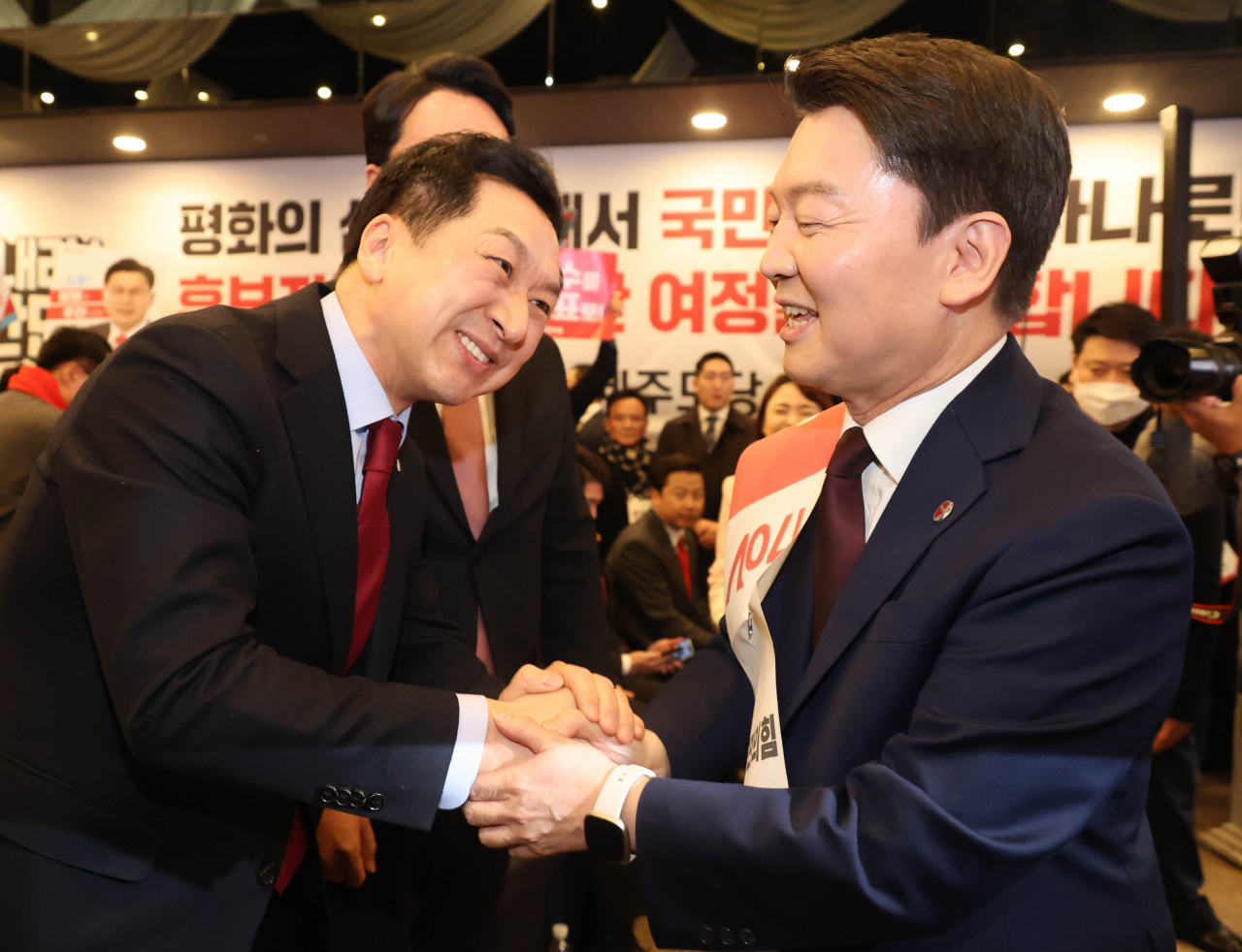Two leading candidates for the ruling People Power Party chair, Reps. Kim Gi-hyeon (left) and Ahn Cheol-soo, shake hands at a hotel in Jeju on Monday. (Yonhap)
