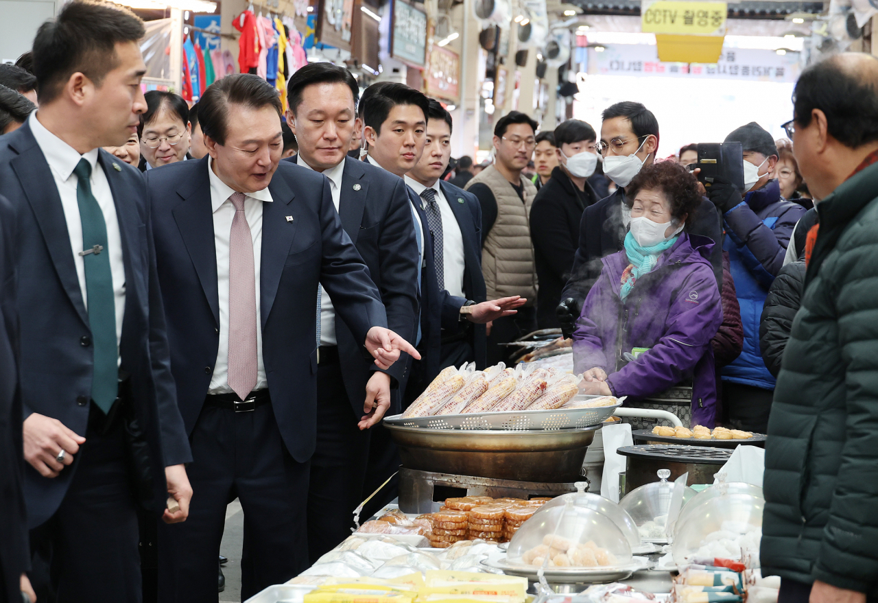 President Yoon Suk Yeol (second from left), points at food during his visit to a traditional market in Cheongju, the capital of North Chungcheong Province, central South Korea, last Tuesday. (Yonhap)