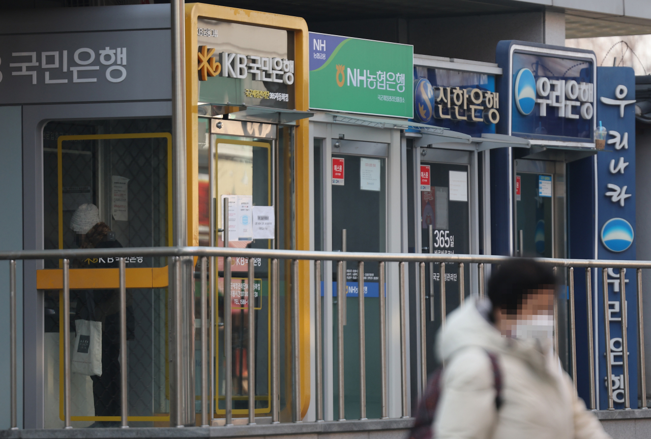 A person passes by a row of ATM machines in Seoul on Feb. 6 (Yonhap)