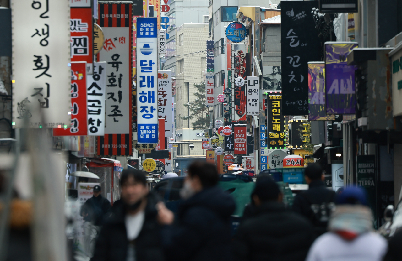 Pedestrians walk along restaurant signs along a back alley in Seoul. (Yonhap)