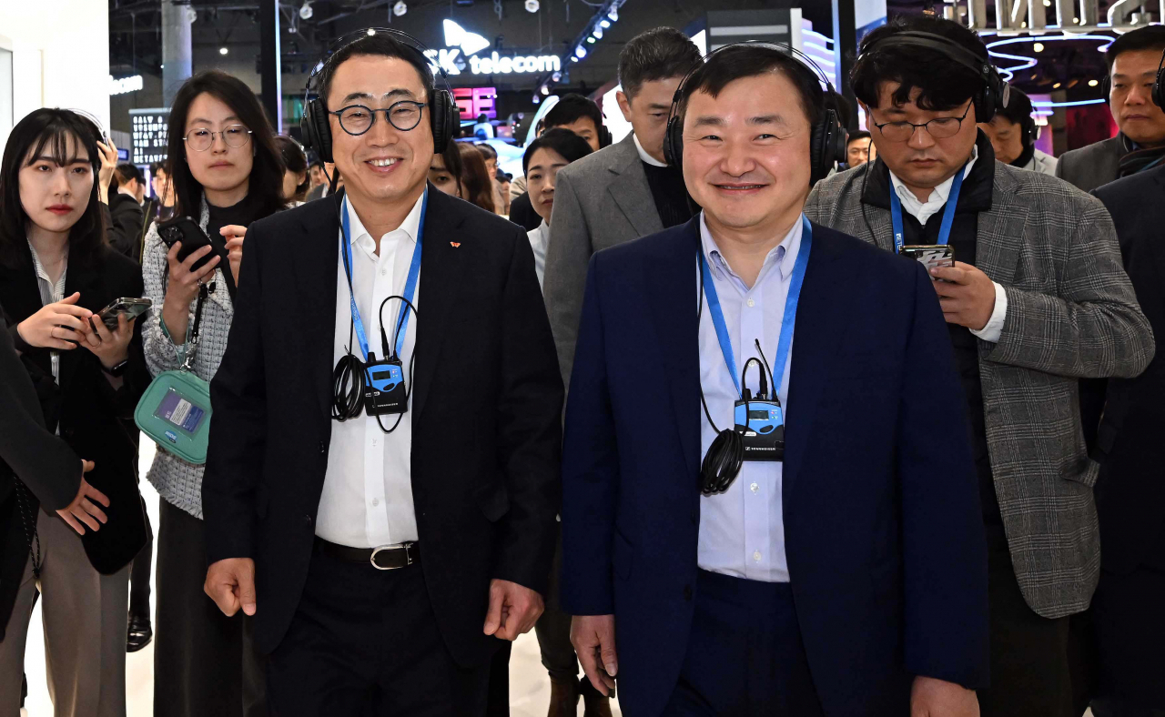 Samsung Electronics President Roh Tae-moon (right) and SK Telecom CEO Ryu Young-sang observe exhibition booths together at the annual Mobile World Congress in Barcelona, Spain, Monday. (Yonhap)