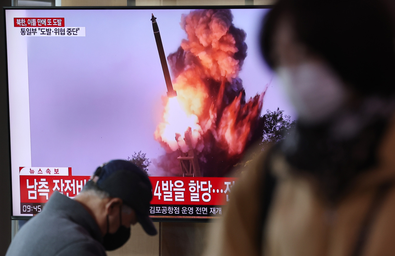 Passersby watch a news report on North Korean missile launches on Feb. 20 at Seoul Station in Seoul. (Yonhap)