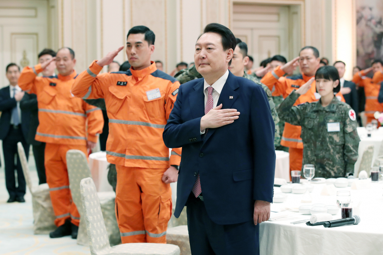 President Yoon Suk Yeol salutes the national flag during a luncheon meeting with the Korea Disaster Relief Team returned from Turkey after aiding post-quake efforts at the guesthouse of Cheong Wa Dae in Seoul on Tuesday. (Yonhap)