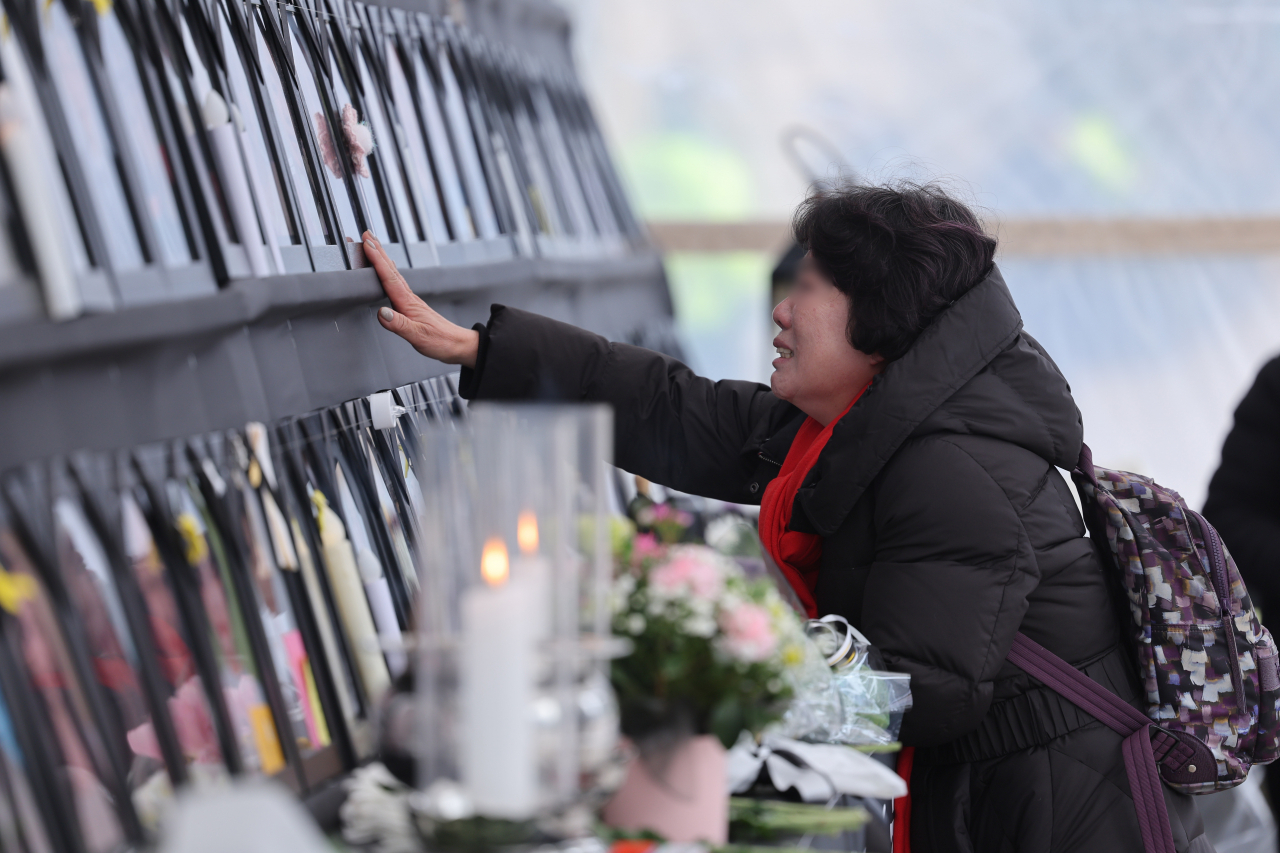 A visitor pays her respects to the victims of the Oct. 29 crowd crush in Itaewon at a memorial altar at Seoul Plaza in February. (Yonhap)