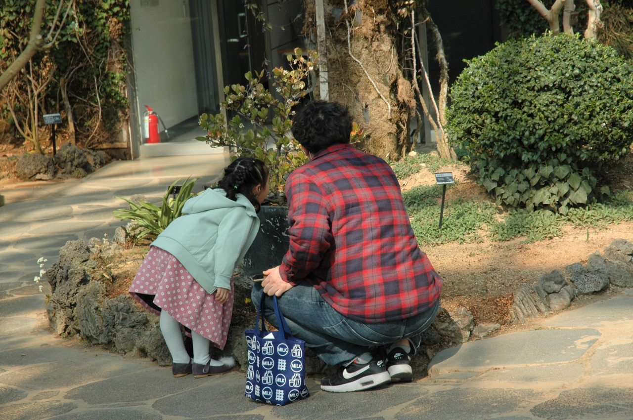 A father smells the spring flowers with his daughter. (Lee Si-jin/The Korea Herald)