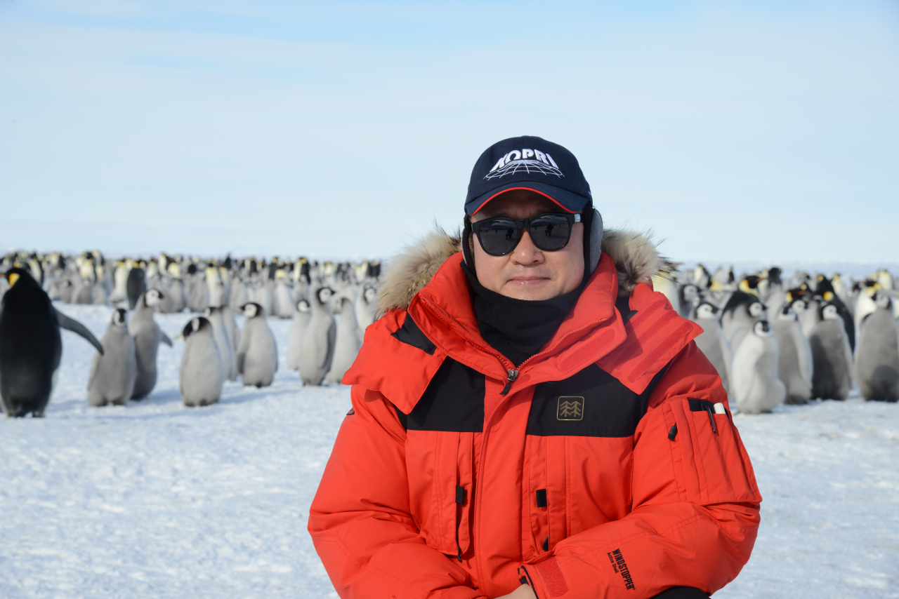 SCAR president Kim Yea-dong poses in front of emperor penguins in Antarctica. (Courtesy of Kim)