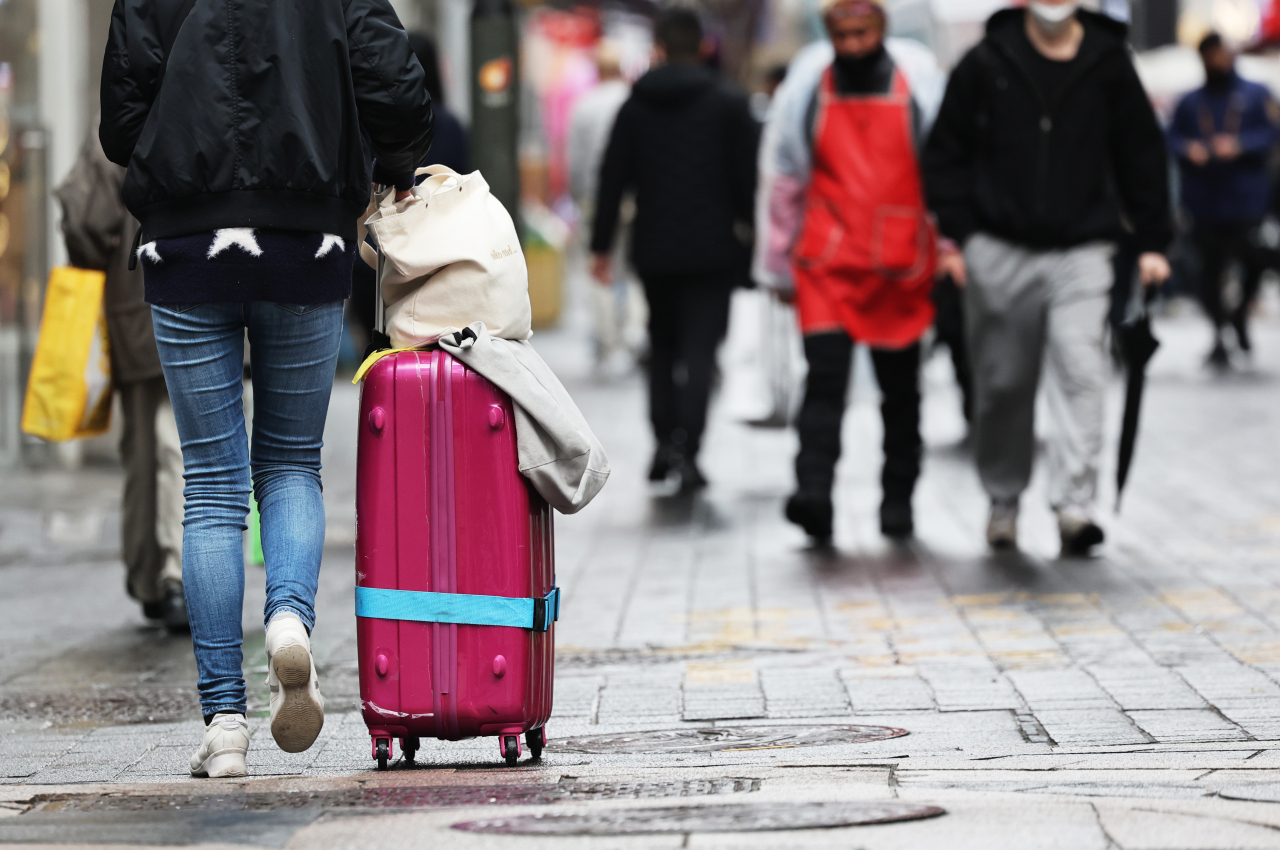 A traveler is seen pulling a suitcase in the Myeong-dong shopping district of central Seoul on March 12. (Yonhap)