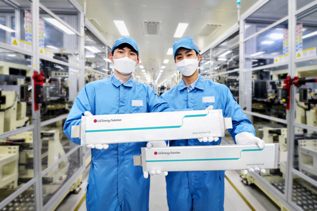 LG Energy Solution employees hold up the battery maker's pouch-type battery cells. (LG Energy Solution)