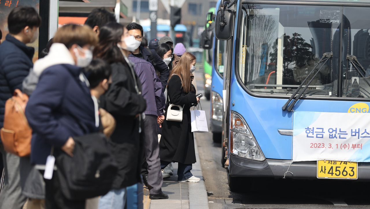 People wait for a bus at a bus stop near Seoul Station in Seoul on Sunday (Yonhap)