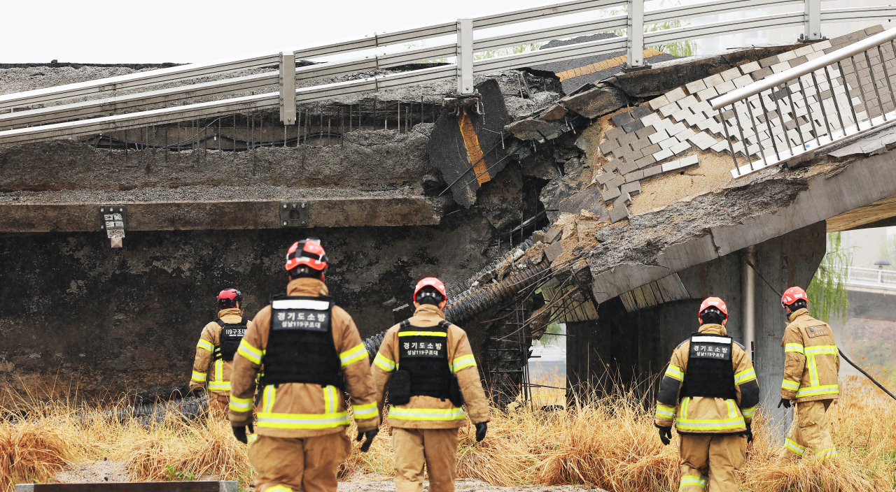 Rescue workers on Thursday scour the site of a bridge collapse in Jeongja-dong in Seongnam, Gyeonggi Province, that left one dead and one injured. (Yonhap)