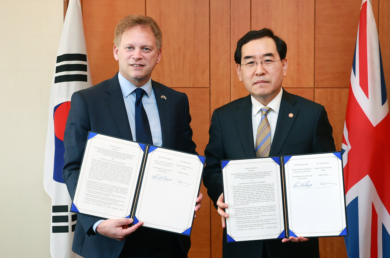 South Korean Industry Minister Lee Chang-yang (right) and British Minister of Department for Energy Security and Net Zero Grant Shapps hold up their joint agreement for cooperation on nuclear power and clean energy in Seoul on Monday. (Yonhap)