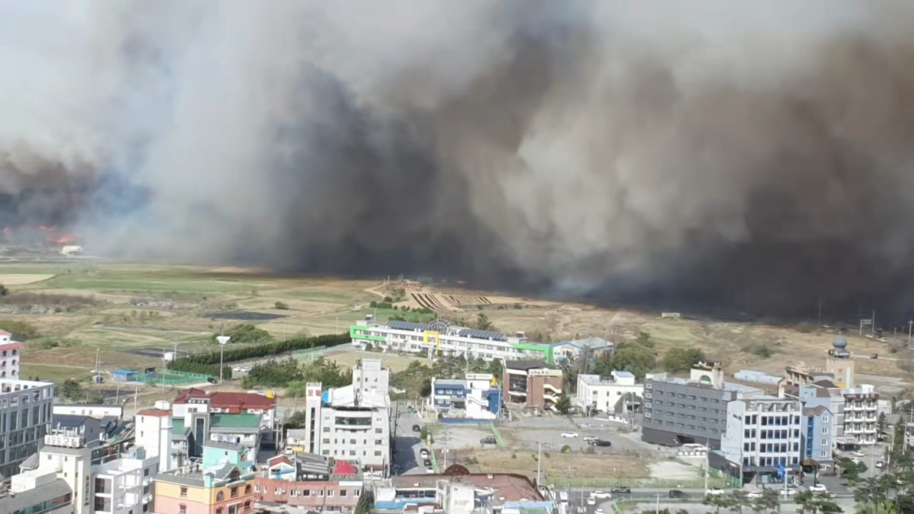 Smoke from a wildfire is seen behind a town in Gangneung, Gangwon Province, on Tuesday morning. (Yonhap)