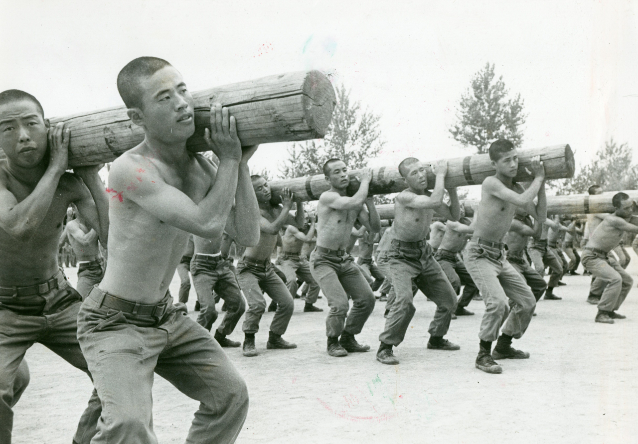 This undated file photo shows inmates at Samchung re-education camp lifting a heavy log as part of a correction program. (The Korea Herald)