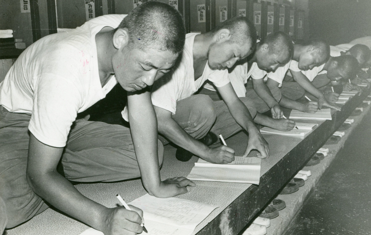 This undated file photo shows inmates at Samchung re-education camp writing apology letters. (The Korea Herald)