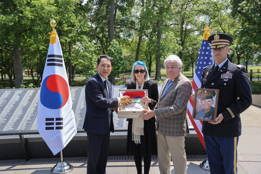 South Korea's Veterans Affairs Minister Park Min-shik (left) and the bereaved family of late Cpl. Luther H. Story, killed during the Korean War, pose for a photo at the Wall of Remembrance at the Korean War Veterans Memorial in Washington on Wednesday. (Ministry of Patriots and Veterans Affairs)