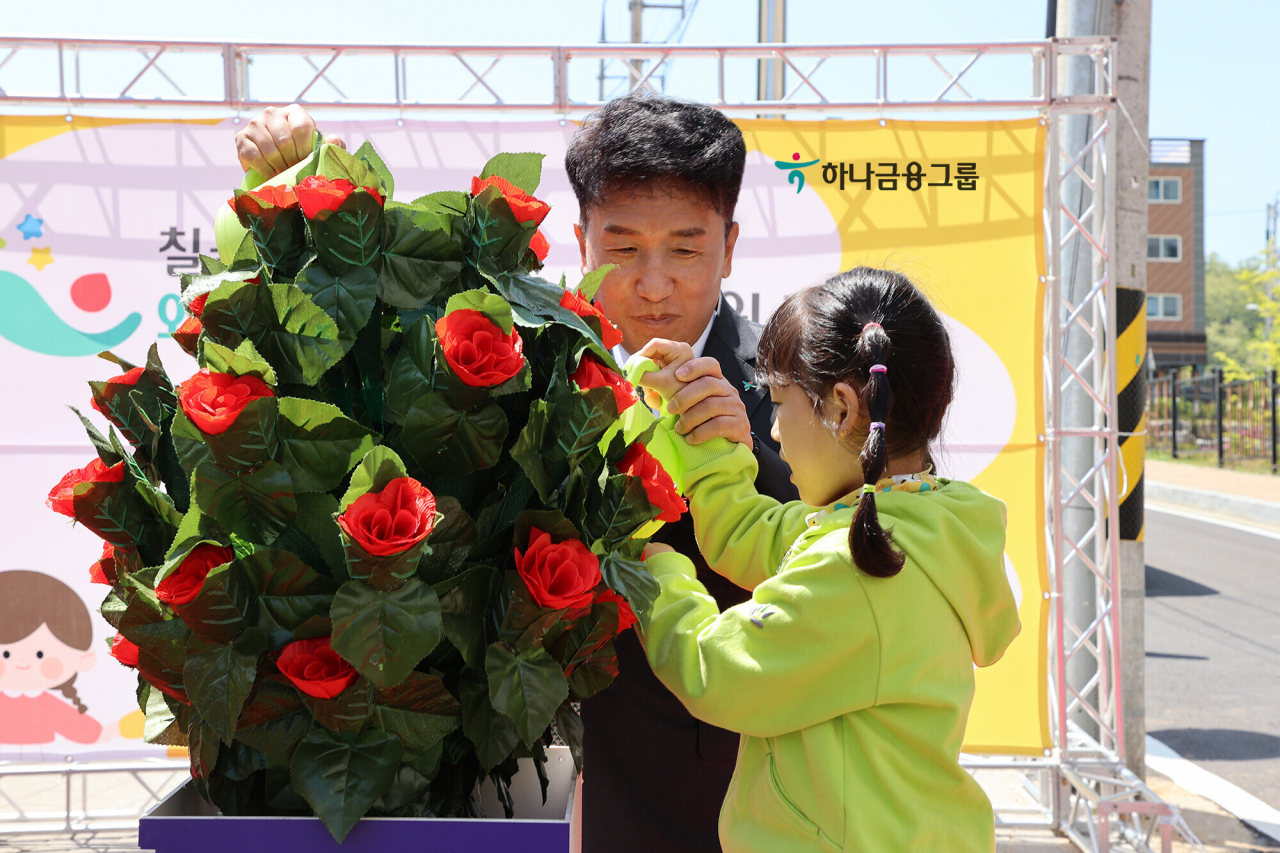 Hana Financial Group Chairman Ham Young-joo and a young student from Chilgok Waegwan Hana Childcare Center water flowers during the facility's opening ceremony on Friday. (Hana Financial Group)